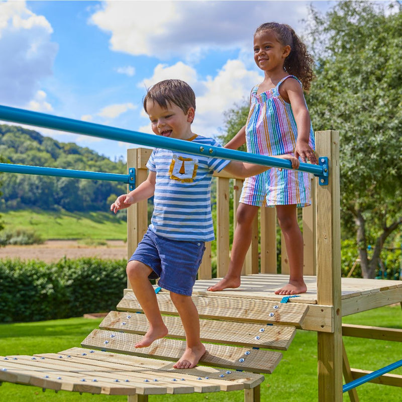 Deux enfants marchent sur le pont suspendu d'une aire de jeux.