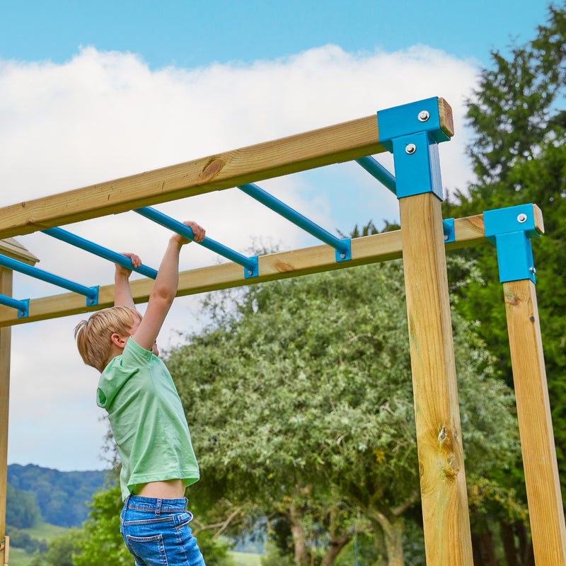 Un enfant se suspend au pont de singe dans un jardin.