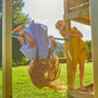 Deux enfants jouent sur une structure en bois, l’un suspendu la tête en bas à une barre, l’autre observant depuis la plateforme