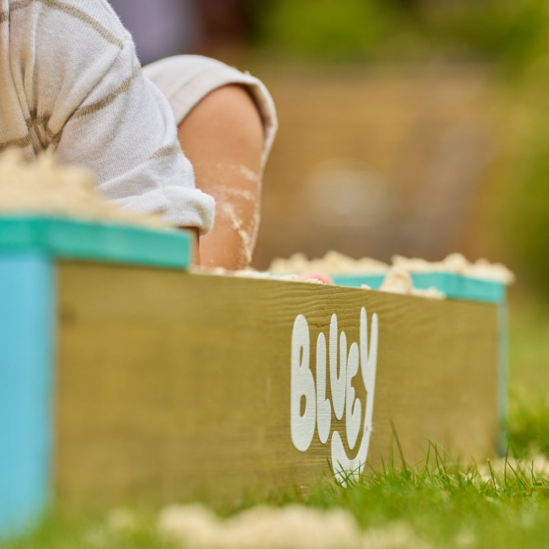 Bac à sable Bluey en bois avec le logo Bluey visible sur le côté.