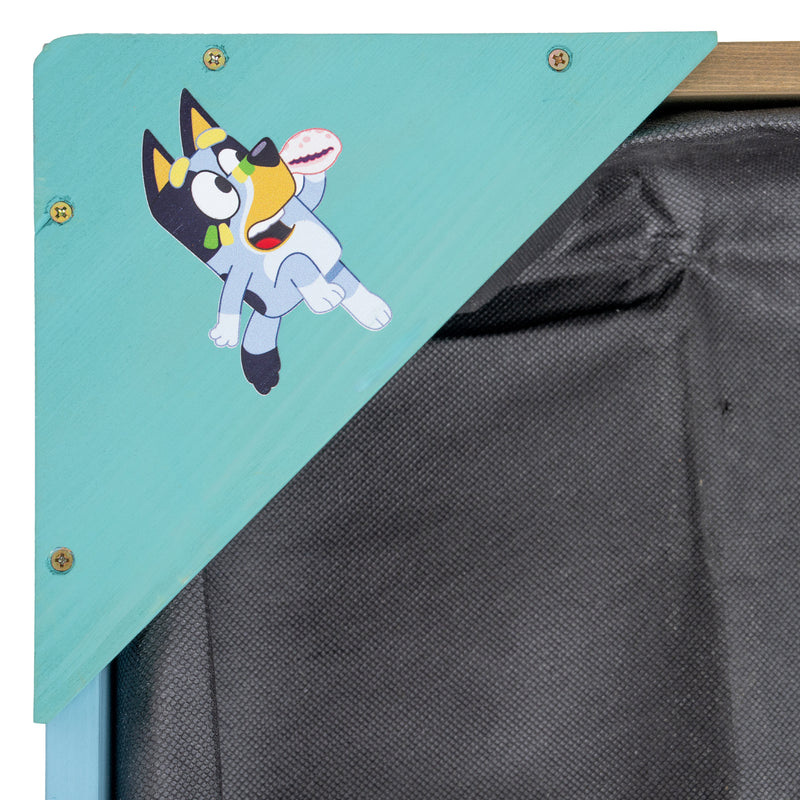 Coin du bac à sable Bluey en bois avec le personnage Bluey posé dessus.