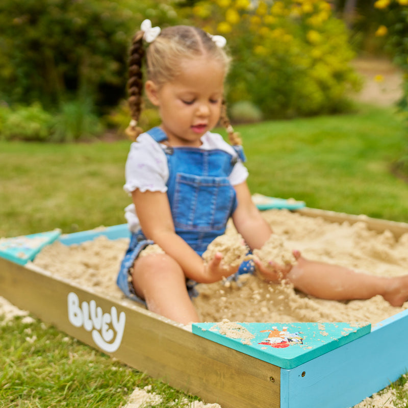 Une enfanr joue dans le bac à sable Bluey.