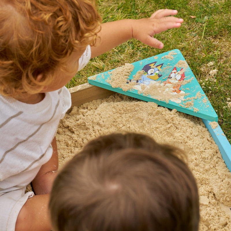 Deux enfants jouent dans le bac à sable Bluey