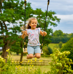 Une enfant se balance sur la balançoire en bois.