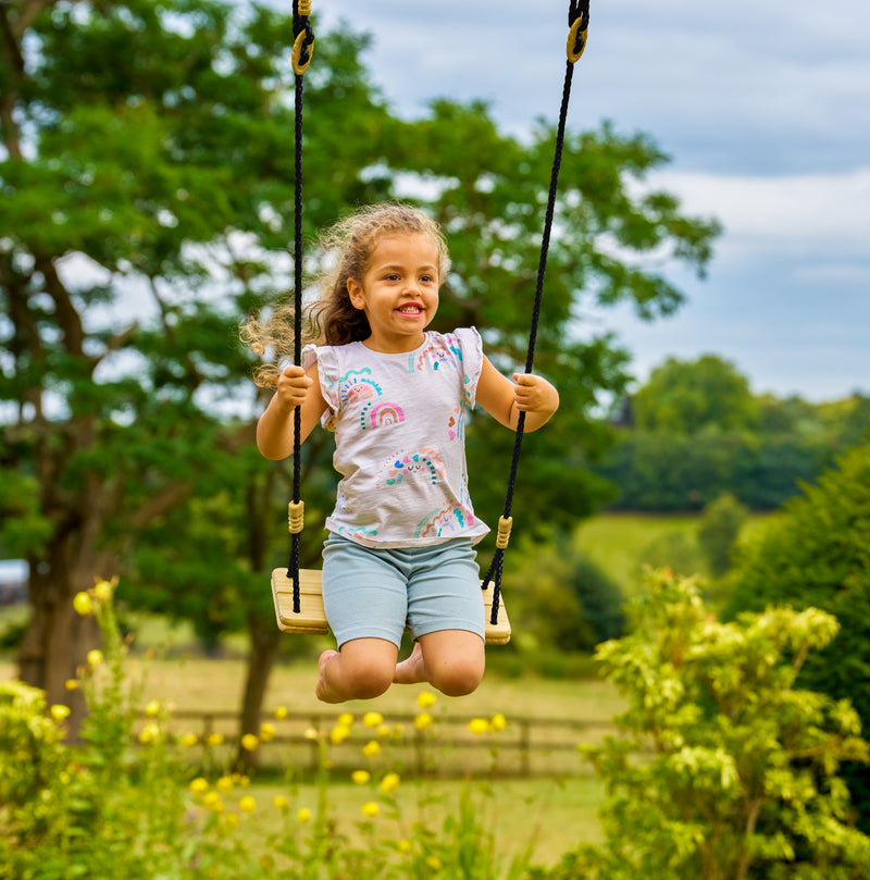 Une enfant se balance sur la balançoire en bois.