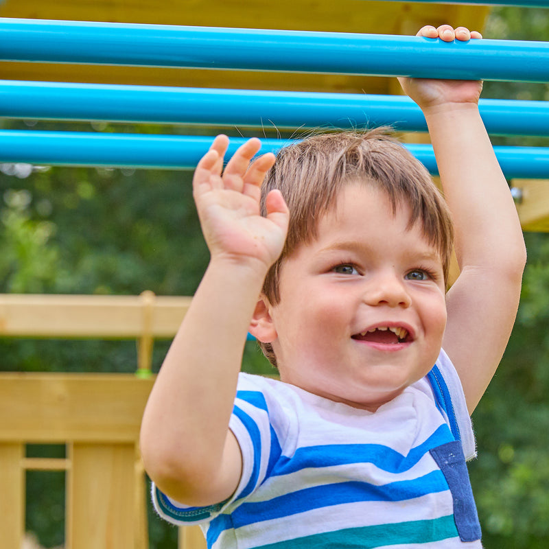 Un enfant se suspend à un pont de singe avec barres en métal et structure en bois.