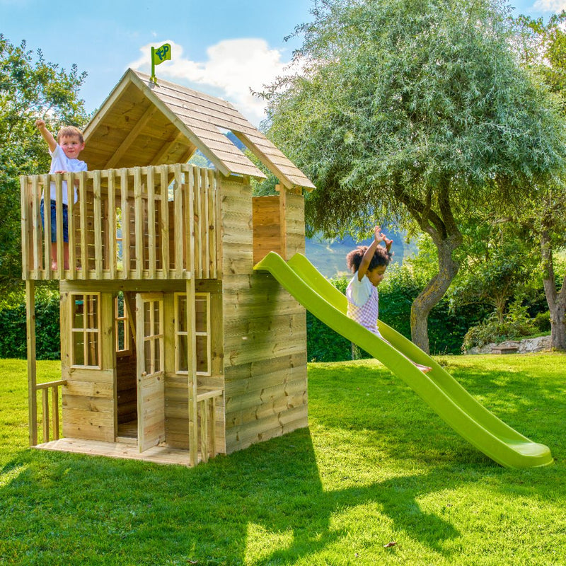 Enfants jouant dans une cabane en bois avec toboggan vert dans un jardin.