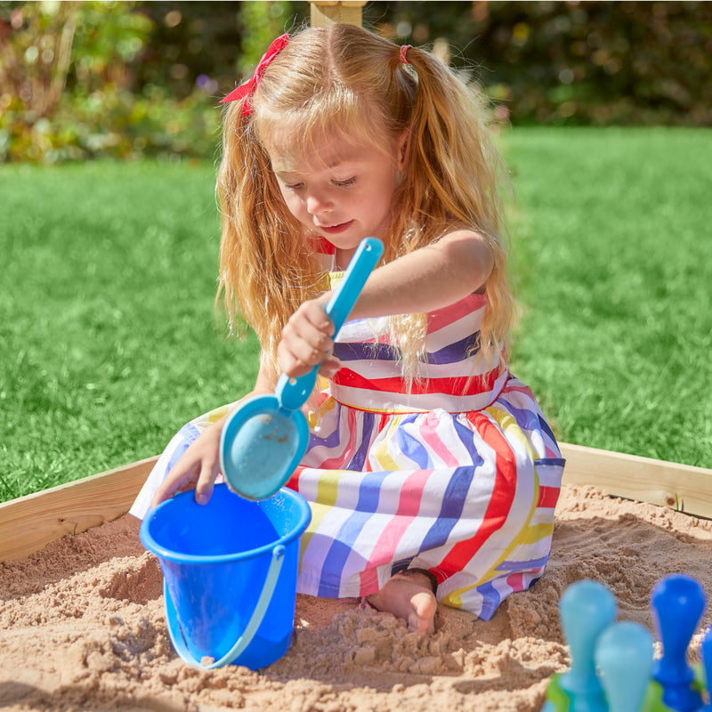 Une enfant se tient sur le balcon d’une cabane en bois sur pilotis.