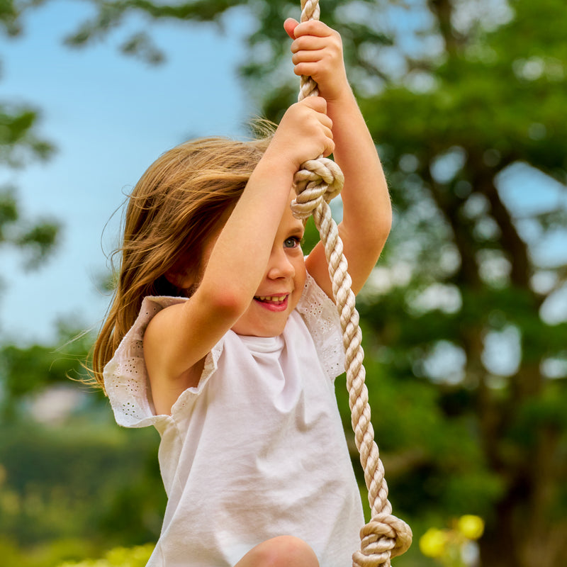 Une enfant se tient à la corde à nœuds TP Toys.