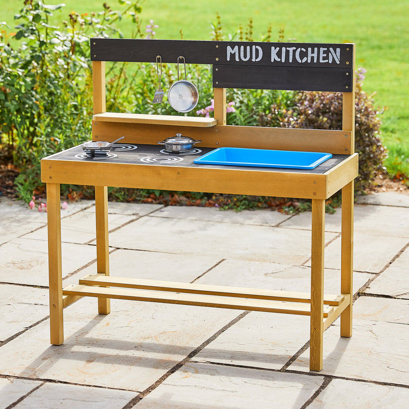 Cuisine en bois pour enfants dans un jardin avec plaque de cuisson peinte, évier amovible en plastique, supports de casserole, comptoir et étagère pour accessoires en acier inoxydable.