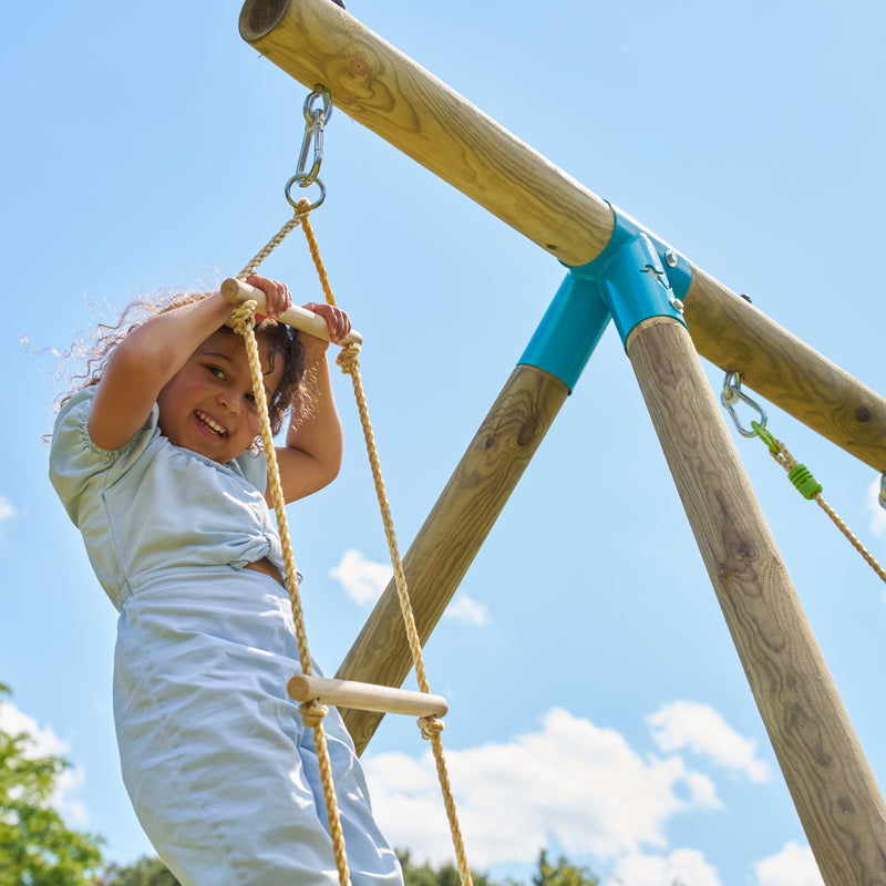 Une enfant grimpe sur l’échelle en bois TP Toys avec cinq barreaux.