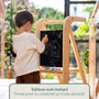 Enfant dessinant à la craie sur le tableau noir intégré de la tour d'apprentissage en bois