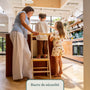 Enfant debout sur la tour d'apprentissage en bois avec barre de sécurité, en famille au plan de travail de la cuisine