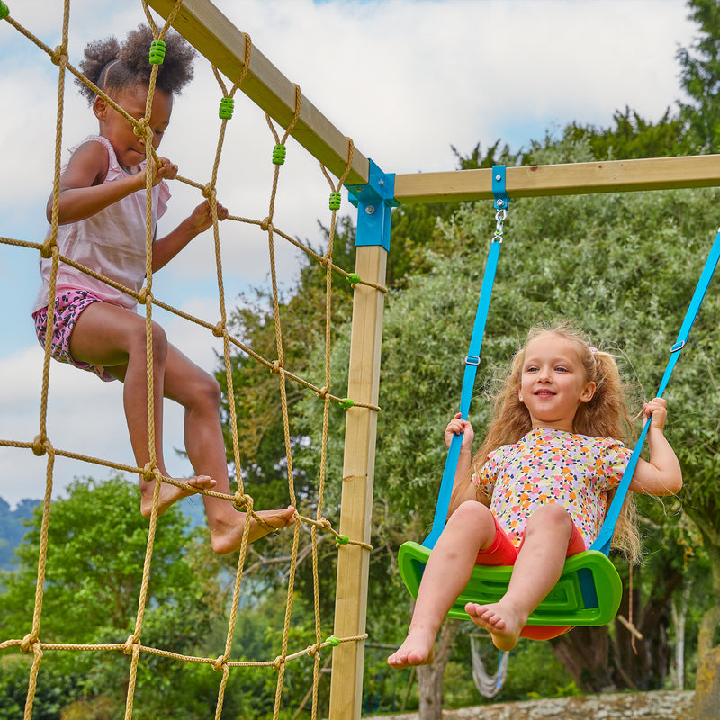Une enfant grimpe le filet d’escalade tandis qu’une autre se balance sur la balançoire.