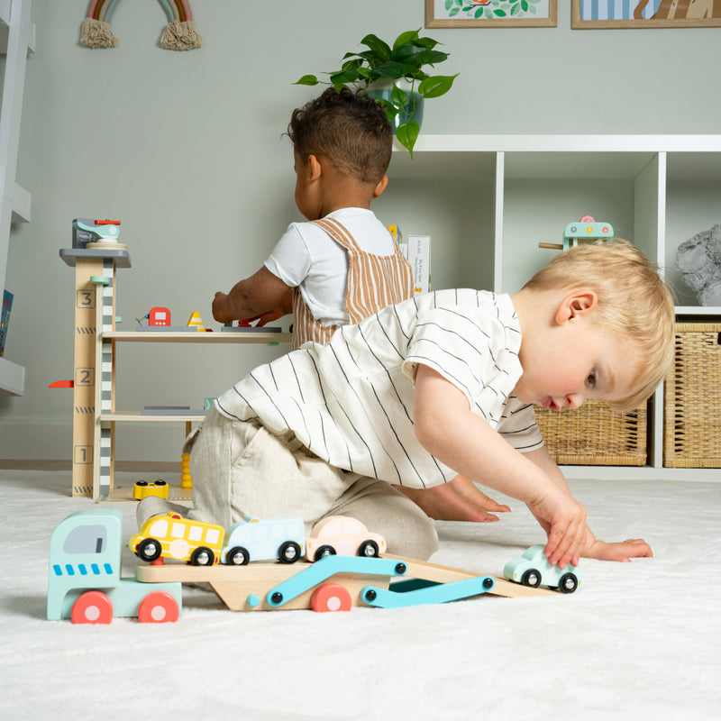 Un enfant place des voitures sur la remorque d’un camion transporteur.