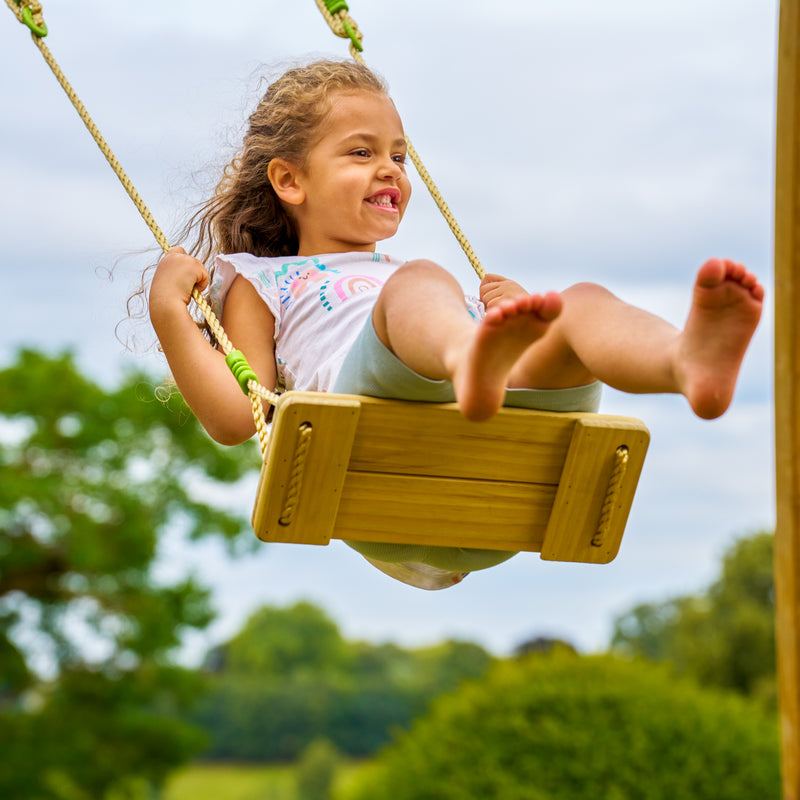 Une enfant se balance sur la balançoire en bois.