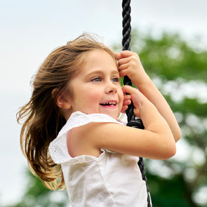 Une enfant se tient à la corde à nœuds TP Toys.