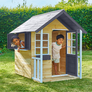Deux enfants jouent dans une maisonnette en bois, installée dans un jardin.