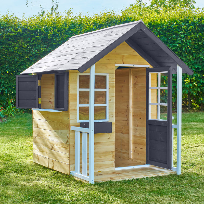 Maisonnette de jardin en bois, porte ouverte et volets, installée sur une pelouse.