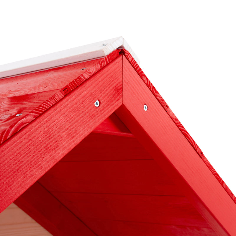 Gros plan sur le toit d’une maisonnette en bois blanche et rouge.