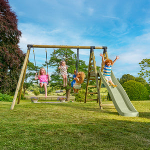 Cinq enfants s’amusent sur un portique en bois dans un jardin. Quatre d’entre eux se balancent sur les balançoires, tandis qu’un glisse sur le toboggan. La scène se déroule sur une pelouse verdoyante, entourée d’arbres, sous un ciel bleu.