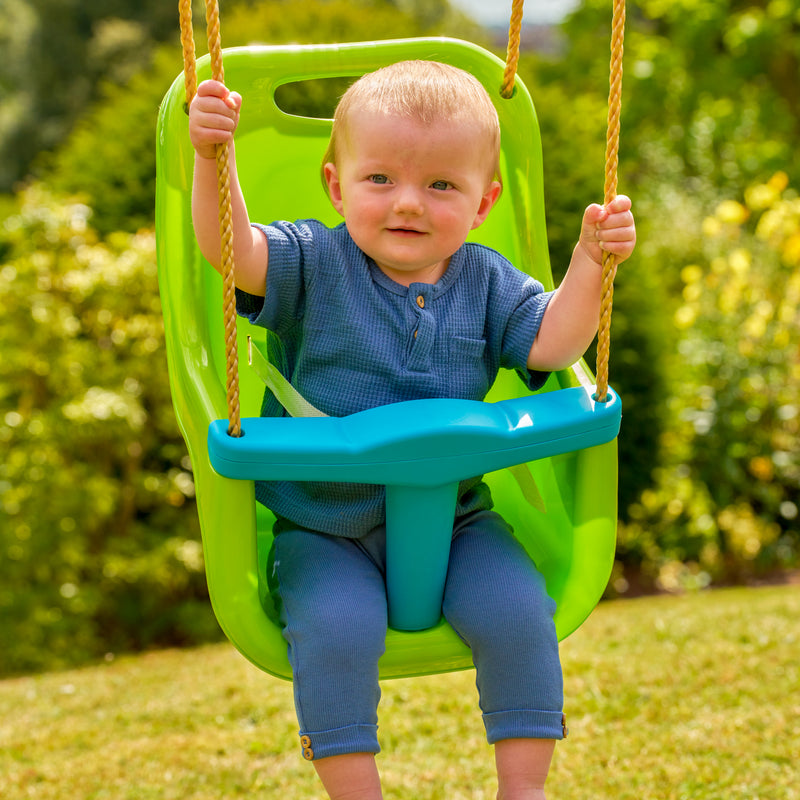 Un enfant est assis dans le siège bébé avec harnais 3 points, fixé à un portique de jeu.