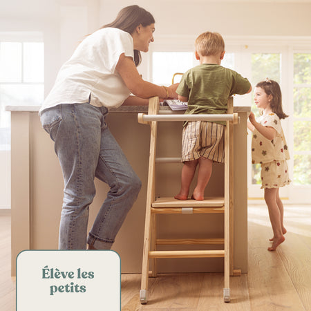Une adulte accompagne deux enfants, dont l’un est en haut d’une tour d’apprentissage.