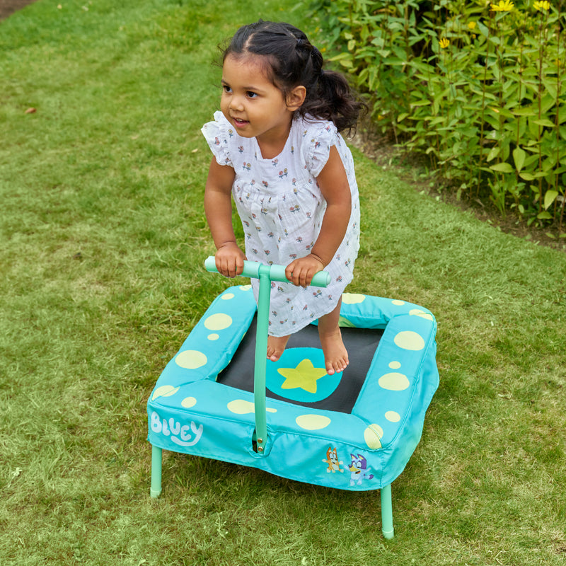 Enfant jouant sur le trampoline Bluey dans un jardin.
