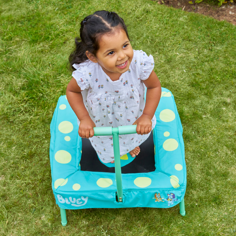 Trampoline Bluey dans un jardin avec un enfant en train de jouer dessus.