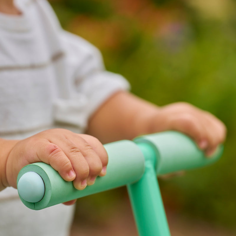 Mains d’un enfant sur les poignées antidérapantes du trampoline Bluey.