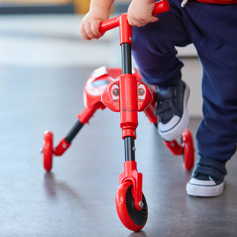 Un enfant s’apprête à monter sur le tricycle pliable SCUTTLEBUG BEETLE rouge et noir.