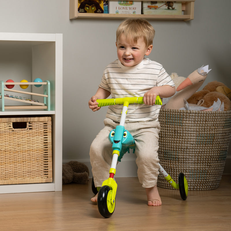 Un enfant est assis sur le tricycle SCUTTLEBUG XL hauteur réglable bleu et vert.