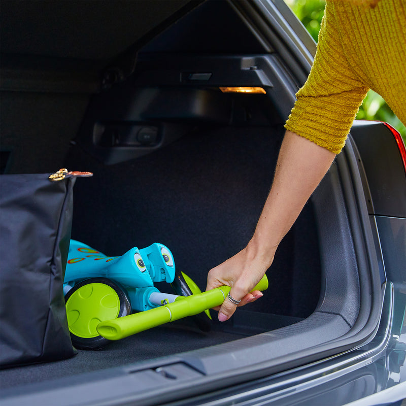 Tricycle SCUTTLEBUG XL hauteur réglable bleu et vert plié rangé dans un coffre de voiture.